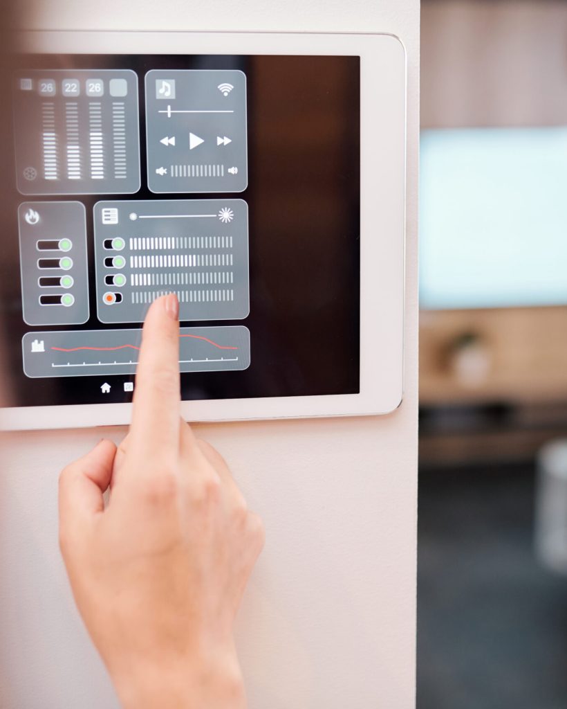 Hand of young woman touching one of digital buttons on smart remote control on the wall